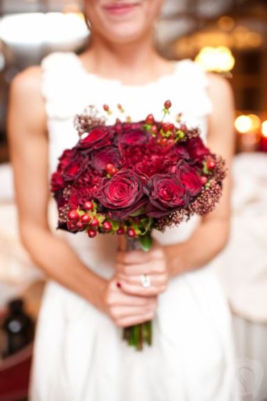 Winter-themed nosegay bouquet with dark red roses and berries Winter-themed nosegay bouquet with dark red roses and berries
